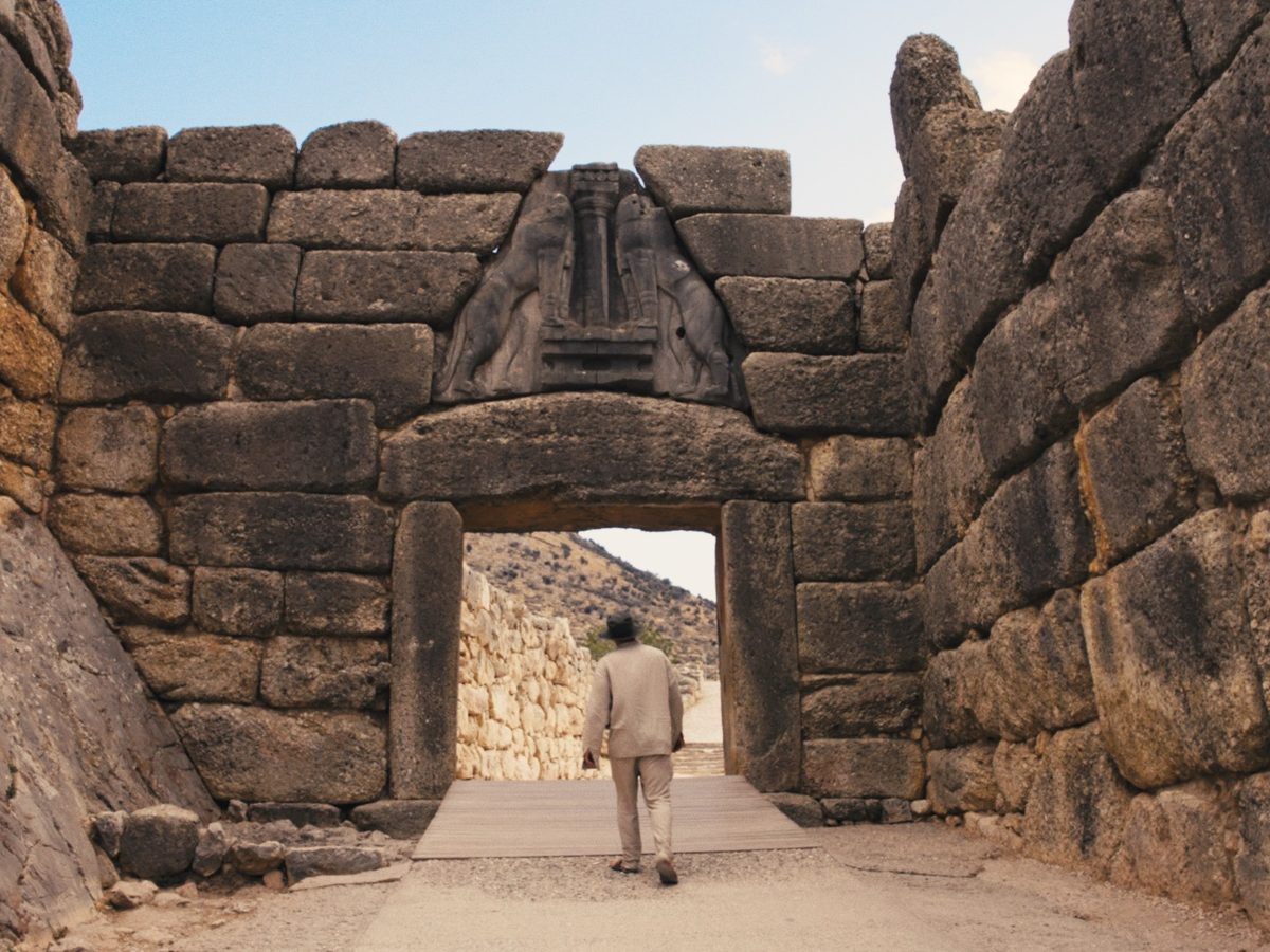 The Lion Gate at Mycenae seen through the Cyclopean passage, a visitor walking through the gate.